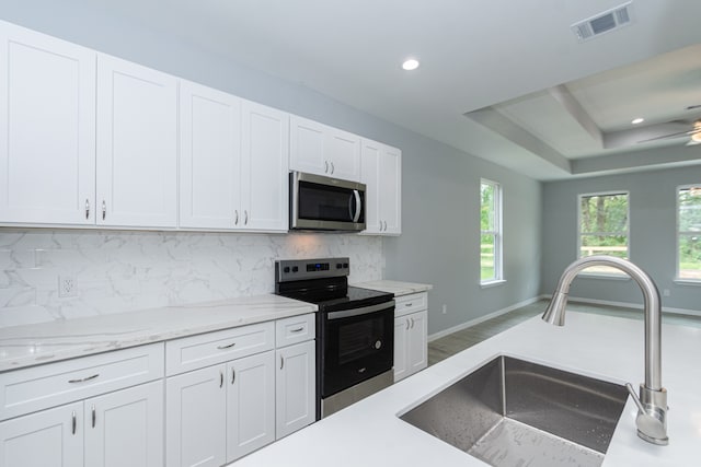 kitchen featuring stainless steel appliances, backsplash, sink, white cabinets, and light hardwood / wood-style floors