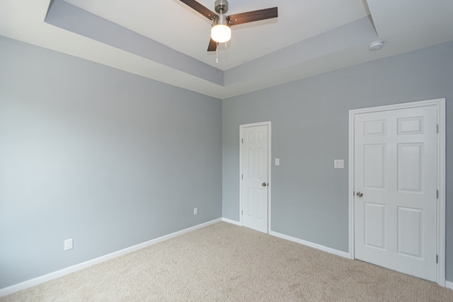 carpeted empty room featuring a tray ceiling and ceiling fan