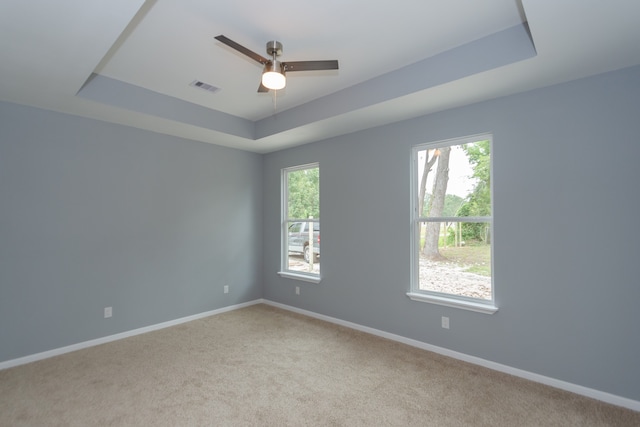 spare room featuring carpet, ceiling fan, and a raised ceiling