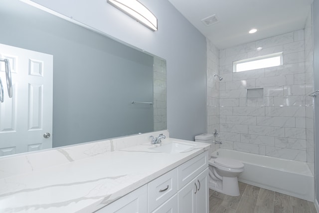 full bathroom featuring tiled shower / bath, vanity, wood-type flooring, and toilet