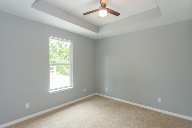 carpeted spare room with ceiling fan and a raised ceiling