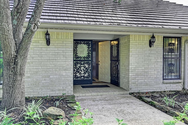 view of exterior entry with brick siding and covered porch