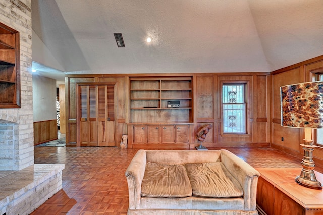 living room featuring built in features, lofted ceiling, a fireplace, and a textured ceiling