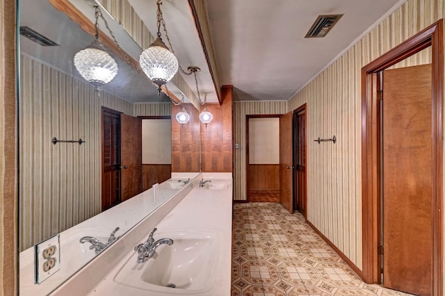 bathroom with wallpapered walls, visible vents, and a sink