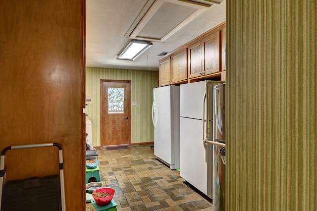 kitchen with visible vents, brick floor, freestanding refrigerator, and brown cabinets