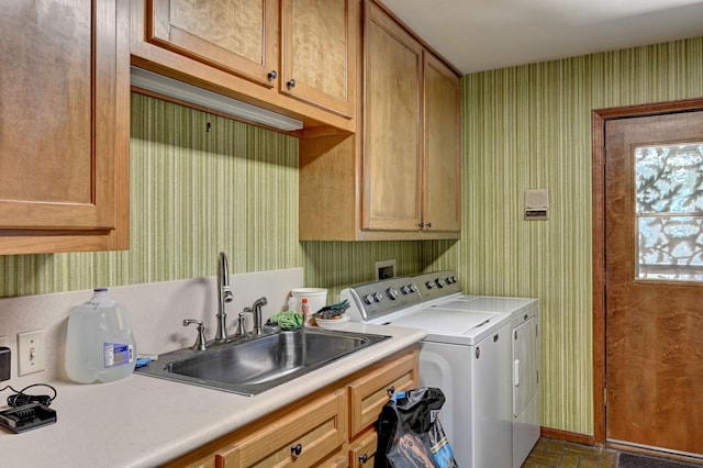 laundry room featuring washing machine and clothes dryer, cabinets, and sink