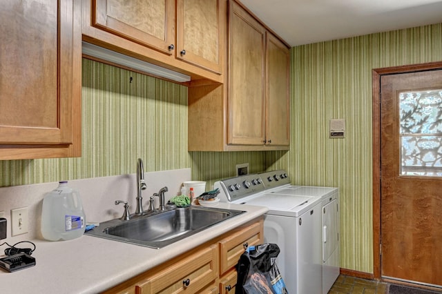 washroom with a sink, washer and dryer, cabinet space, wallpapered walls, and brick floor