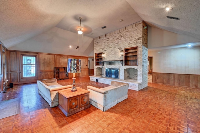 living area featuring lofted ceiling, wooden walls, a fireplace, and a textured ceiling