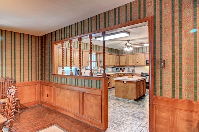 kitchen with wallpapered walls, built in microwave, light countertops, wainscoting, and brick patterned floor