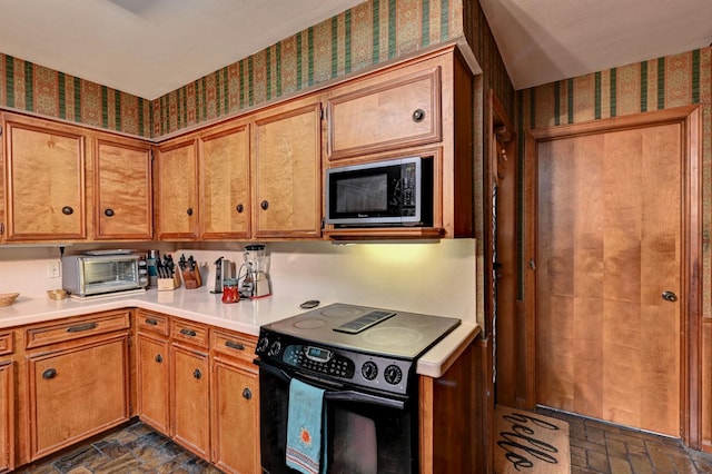 kitchen featuring black / electric stove, a toaster, built in microwave, light countertops, and brown cabinets