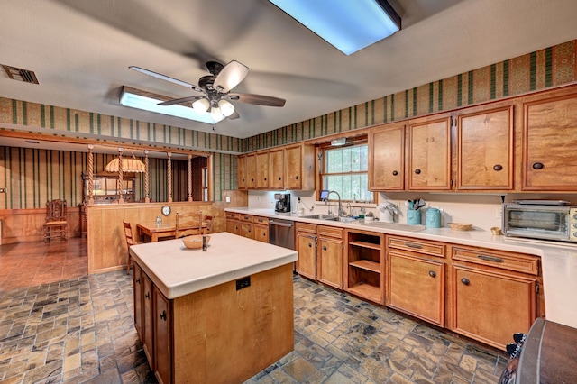 kitchen featuring a skylight, dishwasher, a center island, sink, and ceiling fan