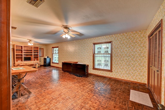 unfurnished living room with a textured ceiling, parquet floors, and ceiling fan