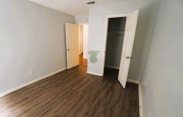 unfurnished bedroom with dark hardwood / wood-style floors and a closet