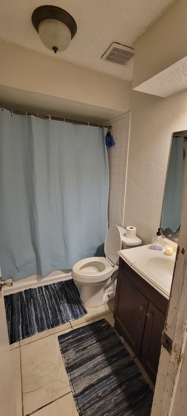 bathroom with a textured ceiling, vanity, toilet, and curtained shower