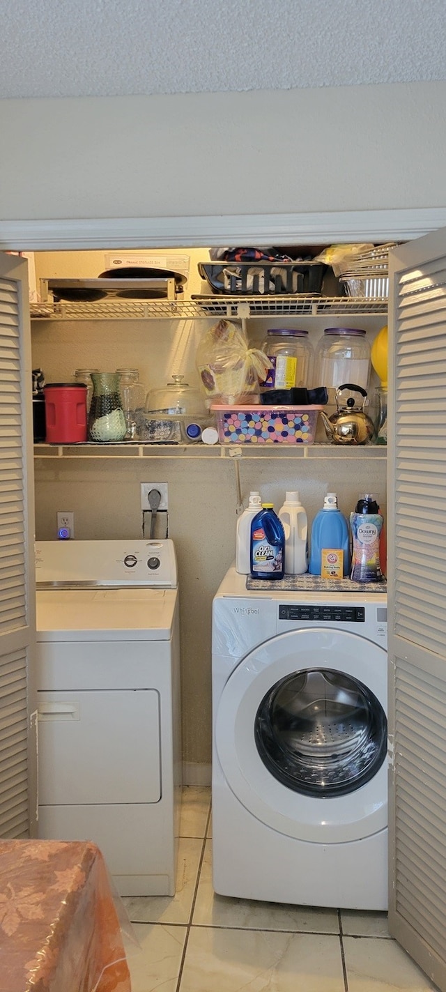 washroom with a textured ceiling, independent washer and dryer, and light tile patterned flooring