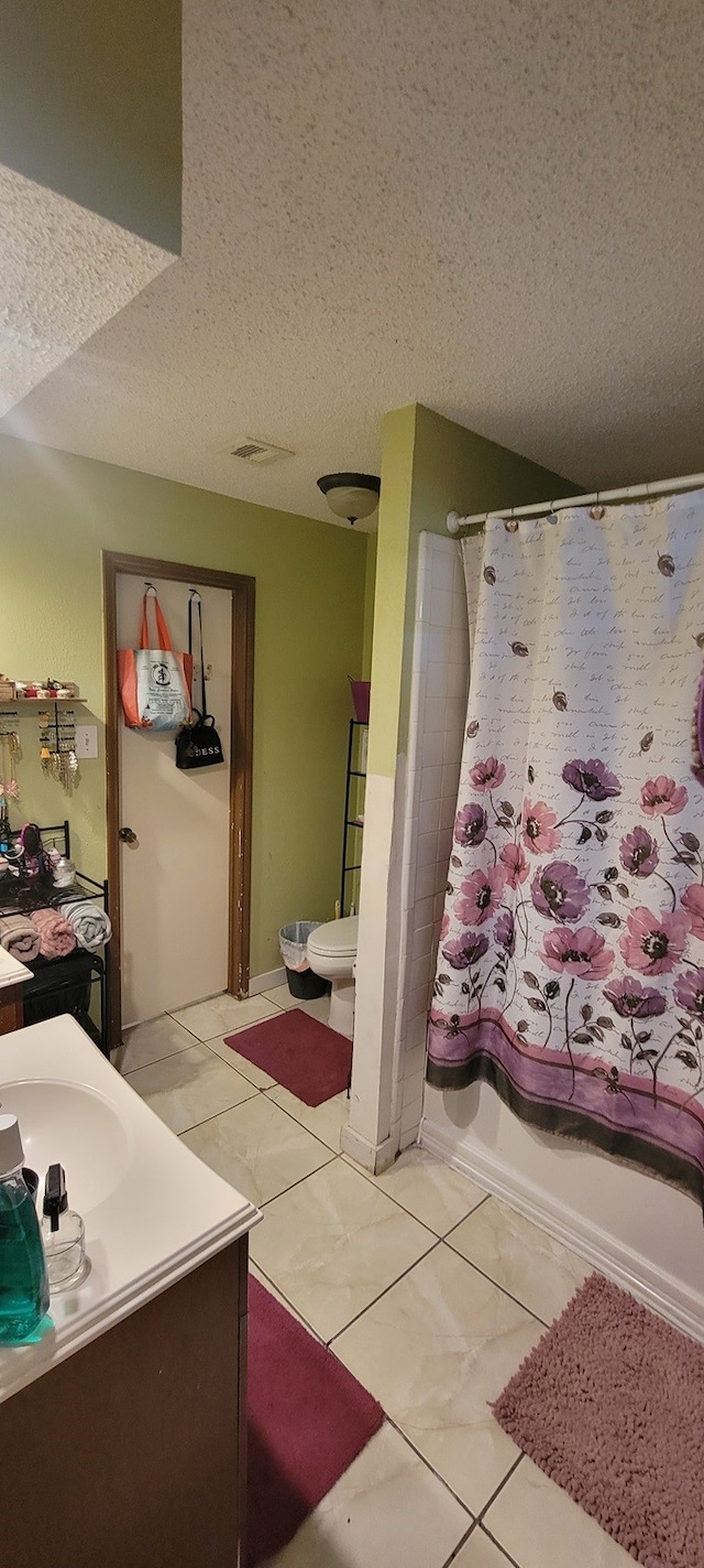 full bathroom with tile patterned flooring, toilet, shower / tub combo, vanity, and a textured ceiling