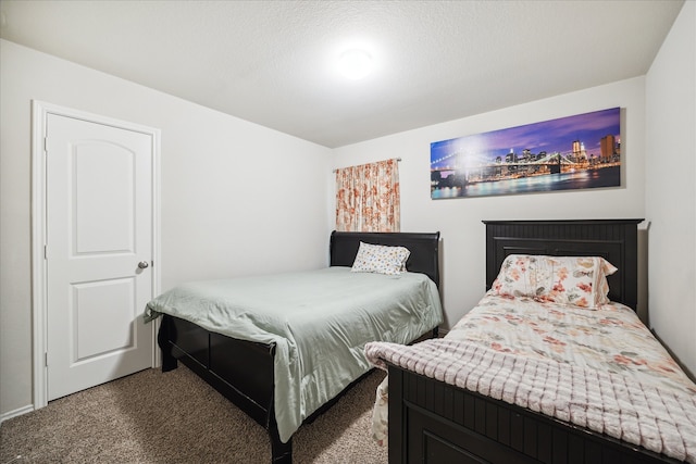 bedroom with a textured ceiling and dark colored carpet