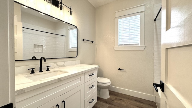 bathroom with hardwood / wood-style flooring, vanity, toilet, and a shower