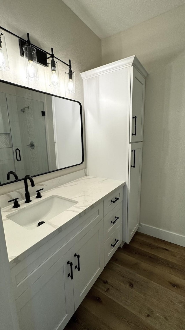 bathroom with a textured ceiling, vanity, wood-type flooring, and an enclosed shower