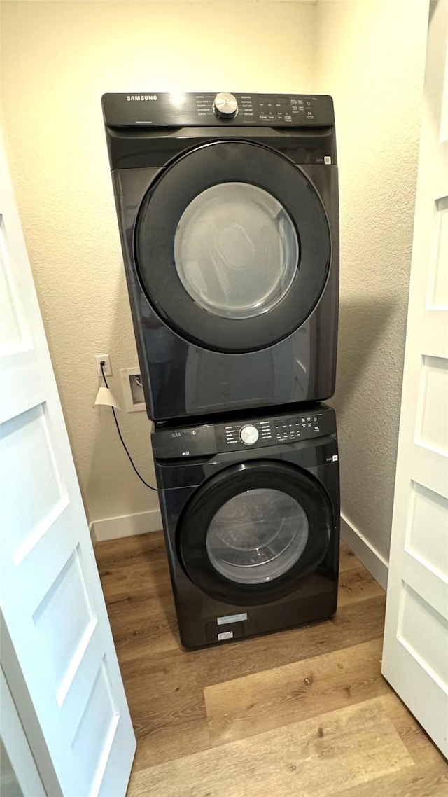 clothes washing area featuring light hardwood / wood-style flooring and stacked washer and clothes dryer