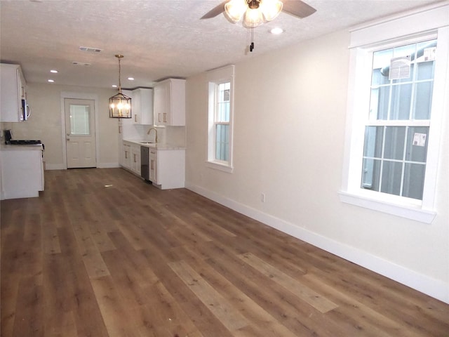 unfurnished living room with a textured ceiling, ceiling fan with notable chandelier, dark hardwood / wood-style flooring, and sink