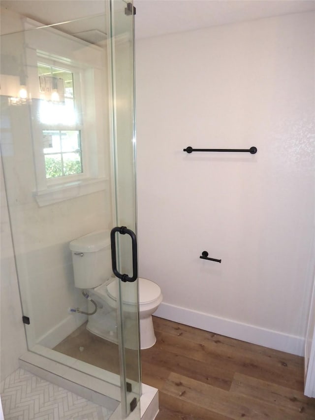 bathroom with hardwood / wood-style floors, toilet, and an enclosed shower