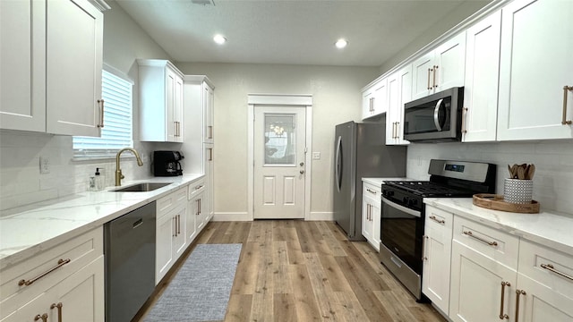 kitchen featuring backsplash, sink, light stone counters, white cabinetry, and stainless steel appliances