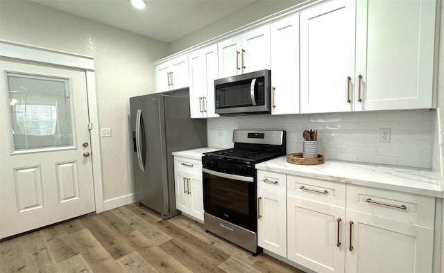 kitchen featuring light stone countertops, appliances with stainless steel finishes, decorative backsplash, and white cabinetry