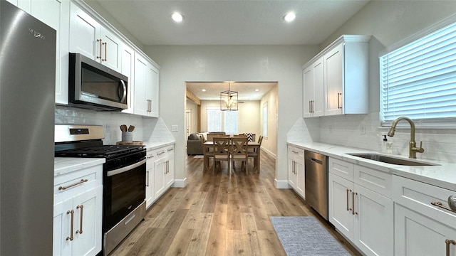 kitchen featuring backsplash, white cabinetry, sink, and appliances with stainless steel finishes