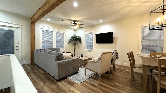 living room with beam ceiling, ceiling fan, dark wood-type flooring, and a textured ceiling