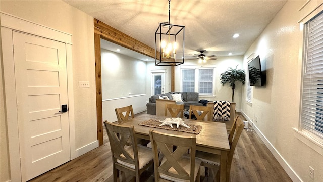 dining room with a textured ceiling, ceiling fan with notable chandelier, and dark hardwood / wood-style floors