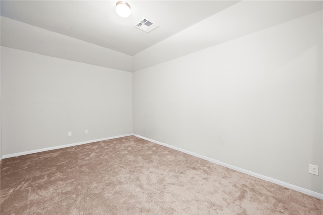 carpeted spare room featuring vaulted ceiling