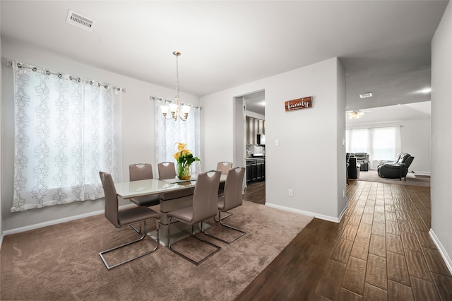 dining space with dark wood-type flooring and an inviting chandelier