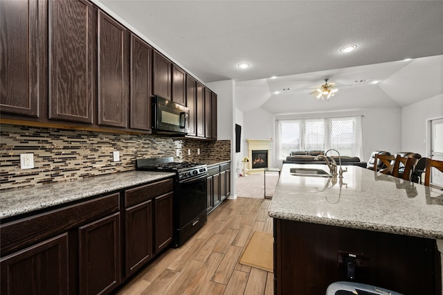 kitchen featuring a kitchen island with sink, black appliances, sink, ceiling fan, and light hardwood / wood-style floors