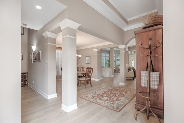 entrance foyer with light hardwood / wood-style flooring, ornamental molding, and ornate columns