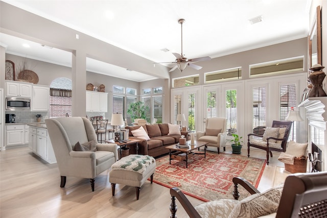 living room with ceiling fan, ornamental molding, and light wood-type flooring