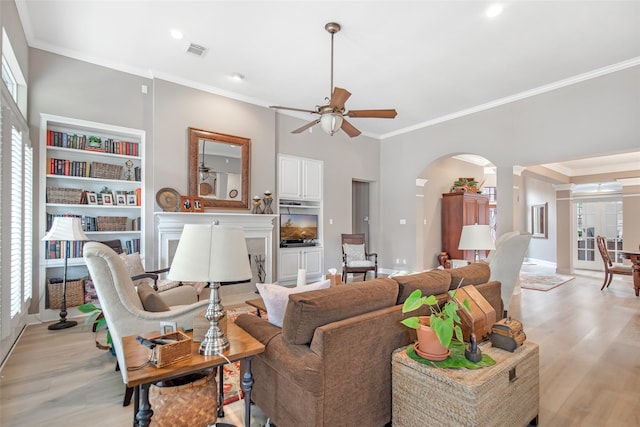 living room featuring a fireplace, crown molding, light hardwood / wood-style flooring, decorative columns, and ceiling fan