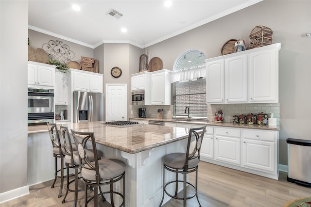 kitchen featuring white cabinetry, a center island, a breakfast bar, appliances with stainless steel finishes, and light hardwood / wood-style floors