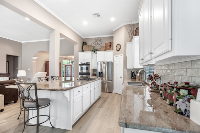 kitchen featuring white cabinets, light hardwood / wood-style flooring, stone counters, a breakfast bar area, and a kitchen island