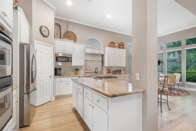 kitchen with crown molding, light hardwood / wood-style flooring, light stone counters, stainless steel appliances, and white cabinetry