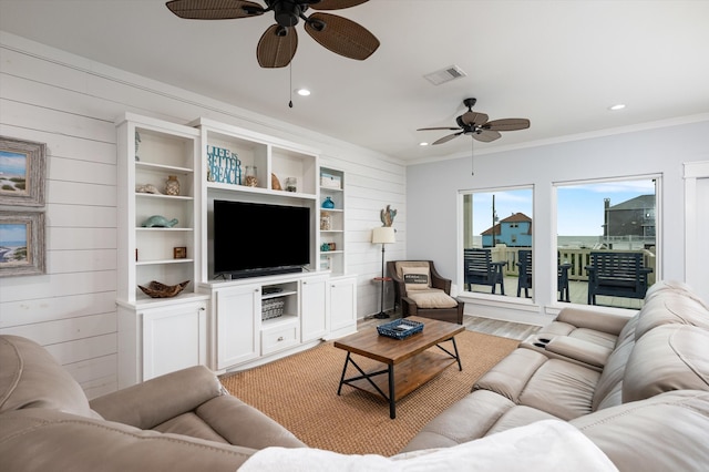 living room with light hardwood / wood-style floors, wood walls, and ceiling fan