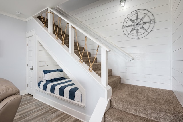 stairs featuring ornamental molding, wood walls, and hardwood / wood-style flooring