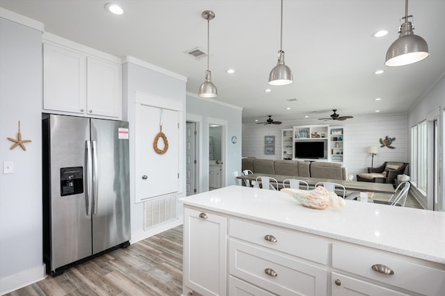 kitchen featuring light hardwood / wood-style flooring, decorative light fixtures, stainless steel fridge, and white cabinetry