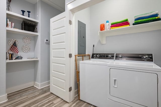 laundry area featuring light wood-type flooring, electric panel, and washer and dryer