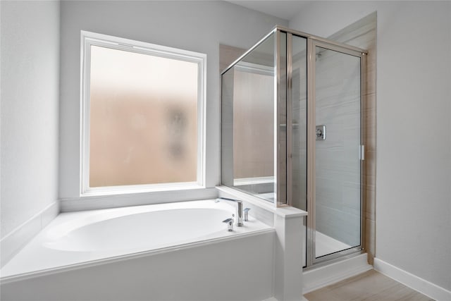 bathroom with a shower stall, baseboards, and a garden tub