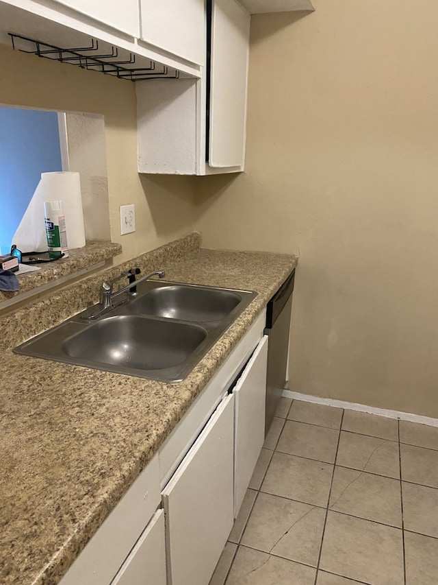 kitchen with stainless steel dishwasher, sink, light tile patterned floors, and white cabinetry