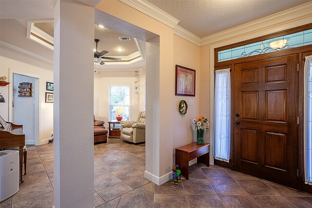 entrance foyer featuring ceiling fan, a raised ceiling, crown molding, and a textured ceiling