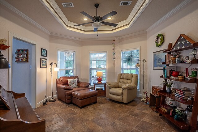 living room featuring a tray ceiling, crown molding, a healthy amount of sunlight, and ceiling fan