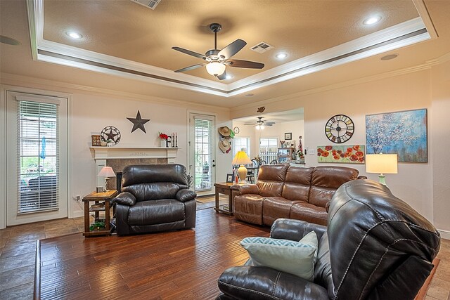 living room featuring a raised ceiling, ceiling fan, dark hardwood / wood-style flooring, and a fireplace