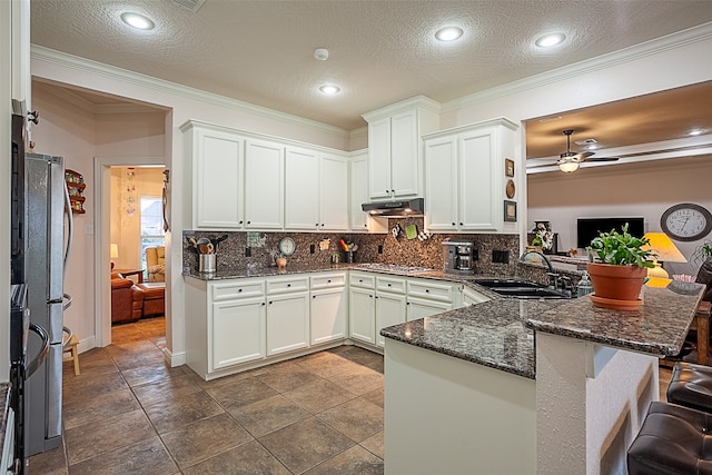 kitchen with dark stone counters, a textured ceiling, kitchen peninsula, sink, and ceiling fan